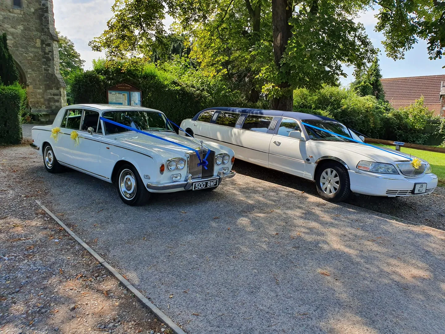 White limousine and white wedding car wrapped with ribbons